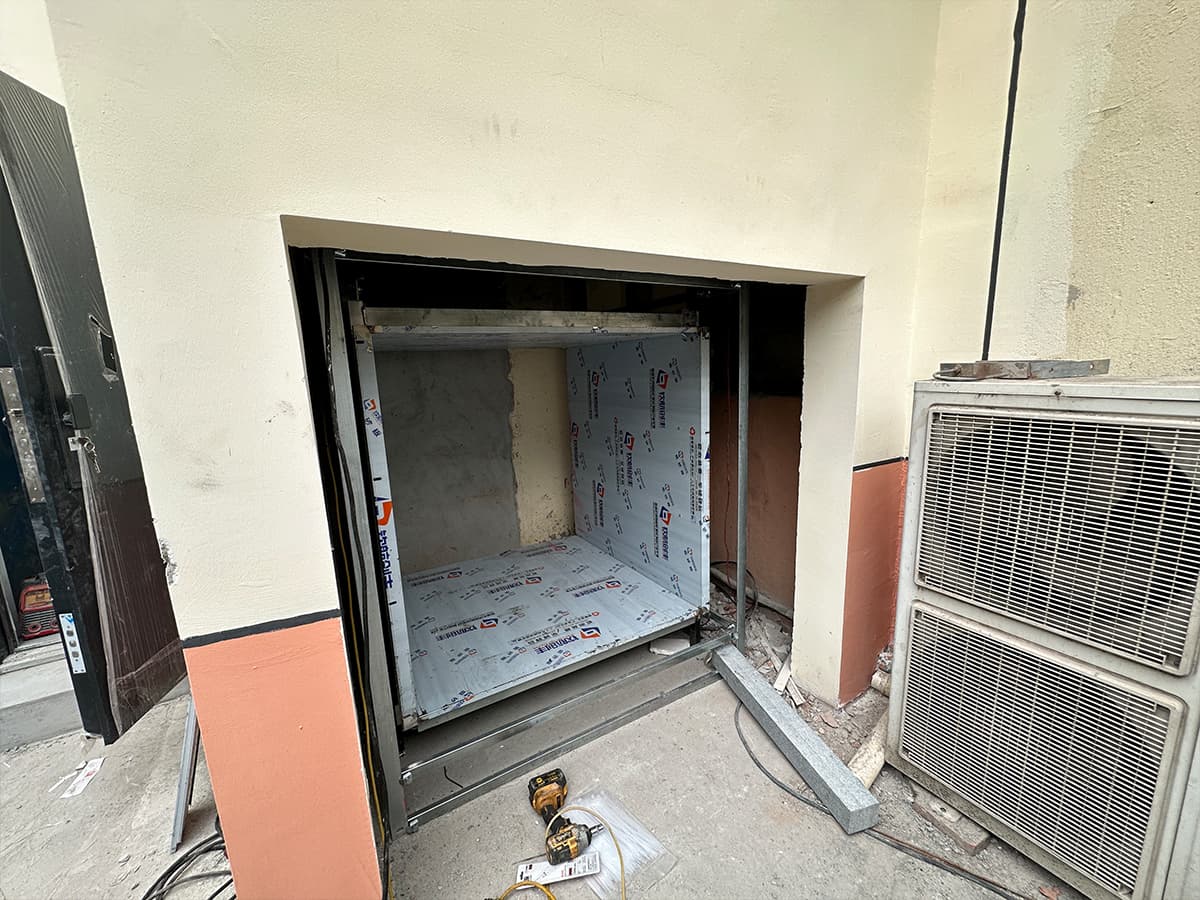 Dumbwaiter installation site: landing opening and car in a brick service shaft before commissioning, Wujiang, Suzhou